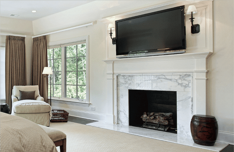 Built-in fireplace surround and hearth in white stone with gray veining, with a TV mounted above