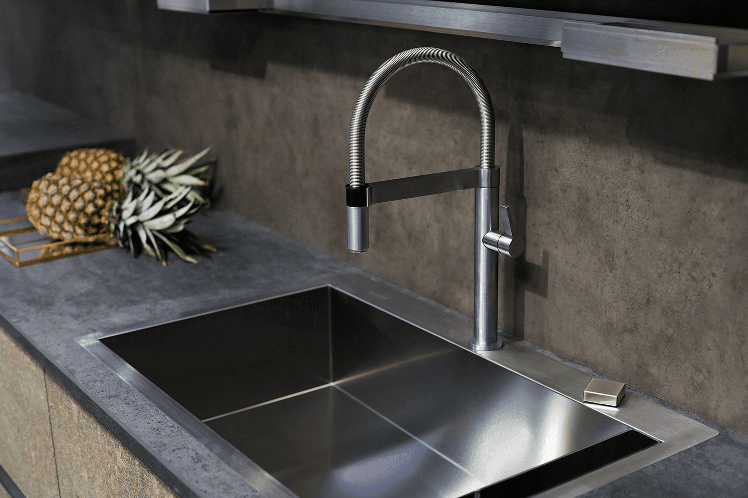 Undermount stainless steel kitchen sink in a dark gray countertop with a modern faucet